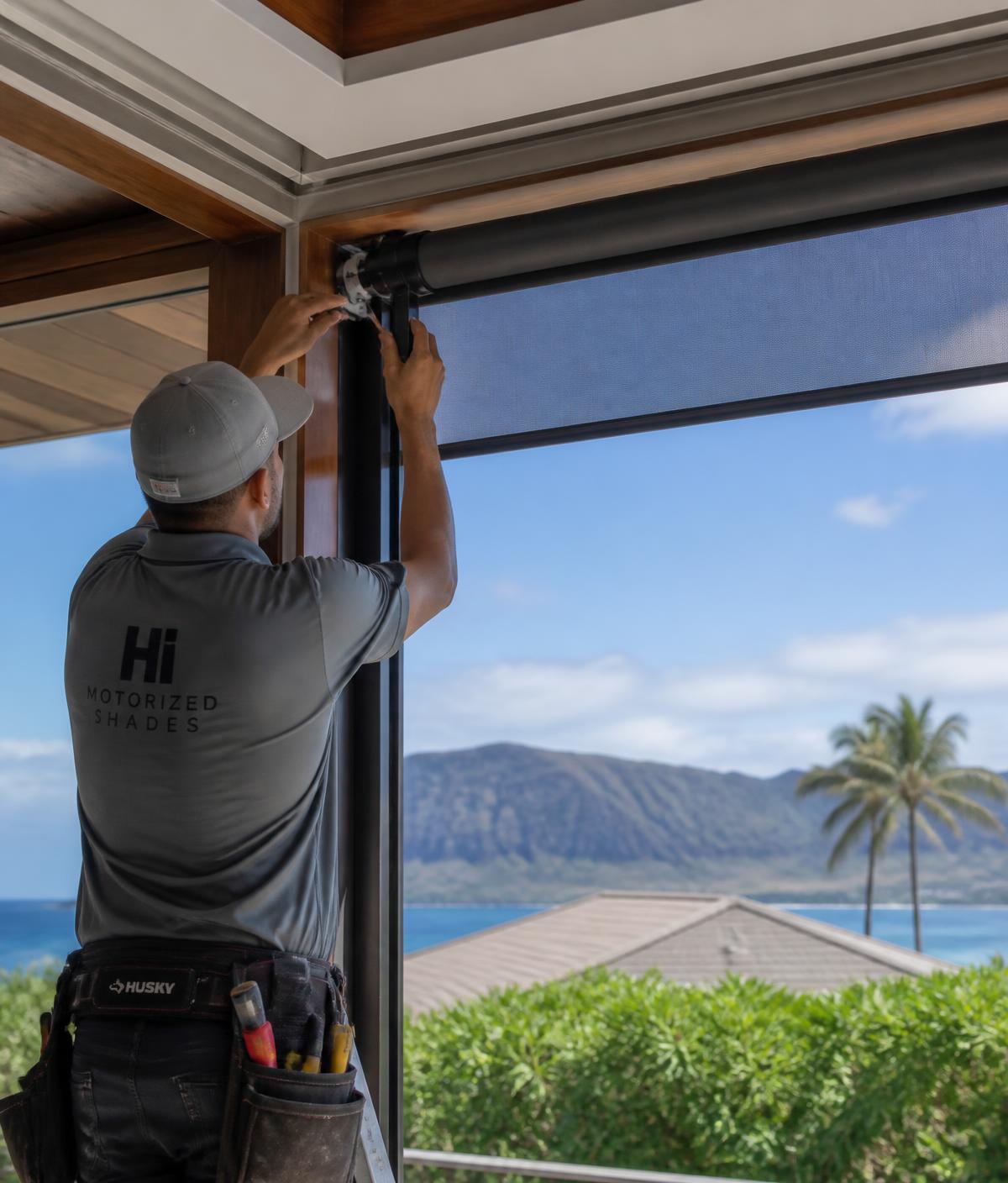 Installer mounting a motorized shade system at an Oahu residence